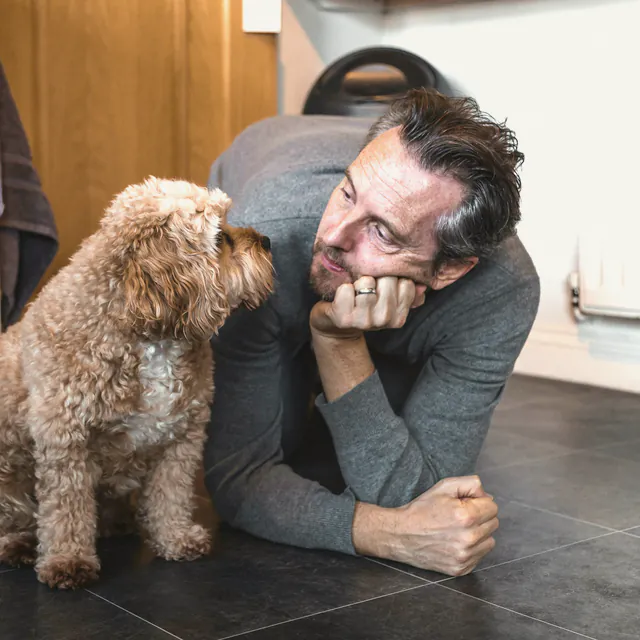 A man holding a small long haired dog