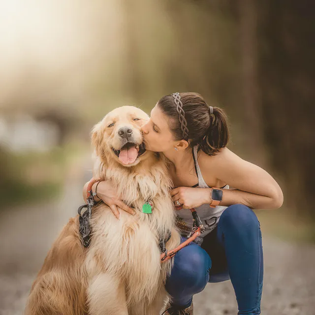 A woman kissing her dog on the cheek