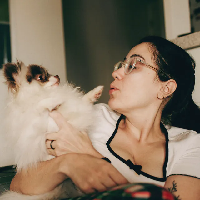 A woman holding a small fluffy dog
